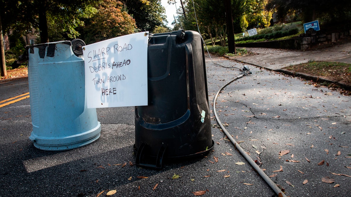 Handwritten warning signs are taped to garbage cans on a street blocked by a tree downed after the passage of Hurricane Zeta, Thursday, Oct. 29, 2020, in Decatur, Ga., a suburb of Atlanta.