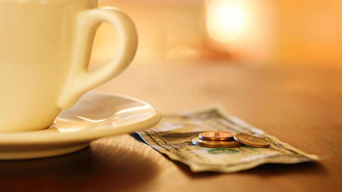 Cash tip on counter next to coffee mug.