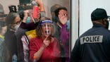 Election challengers yell as they look through the windows of the central counting board as police were helping to keep additional challengers from entering due to overcrowding, Wednesday, Nov. 4, 2020, in Detroit. (AP Photo/Carlos Osorio)