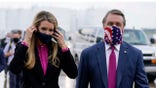 FILE- In this July 15, 2020, file photo Sen. Kelly Loeffler, R-Ga., puts on a face mask as she walks with Sen. David Perdue, R-Ga., right, at UPS Hapeville Airport Hub in Atlanta. (AP Photo/Evan Vucci, File)