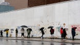 People under umbrellas practice social distancing as they line up for early voting, Friday, Oct. 30, 2020, in the Brooklyn borough of New York. The national election is Nov. 3. (AP Photo/Mark Lennihan)