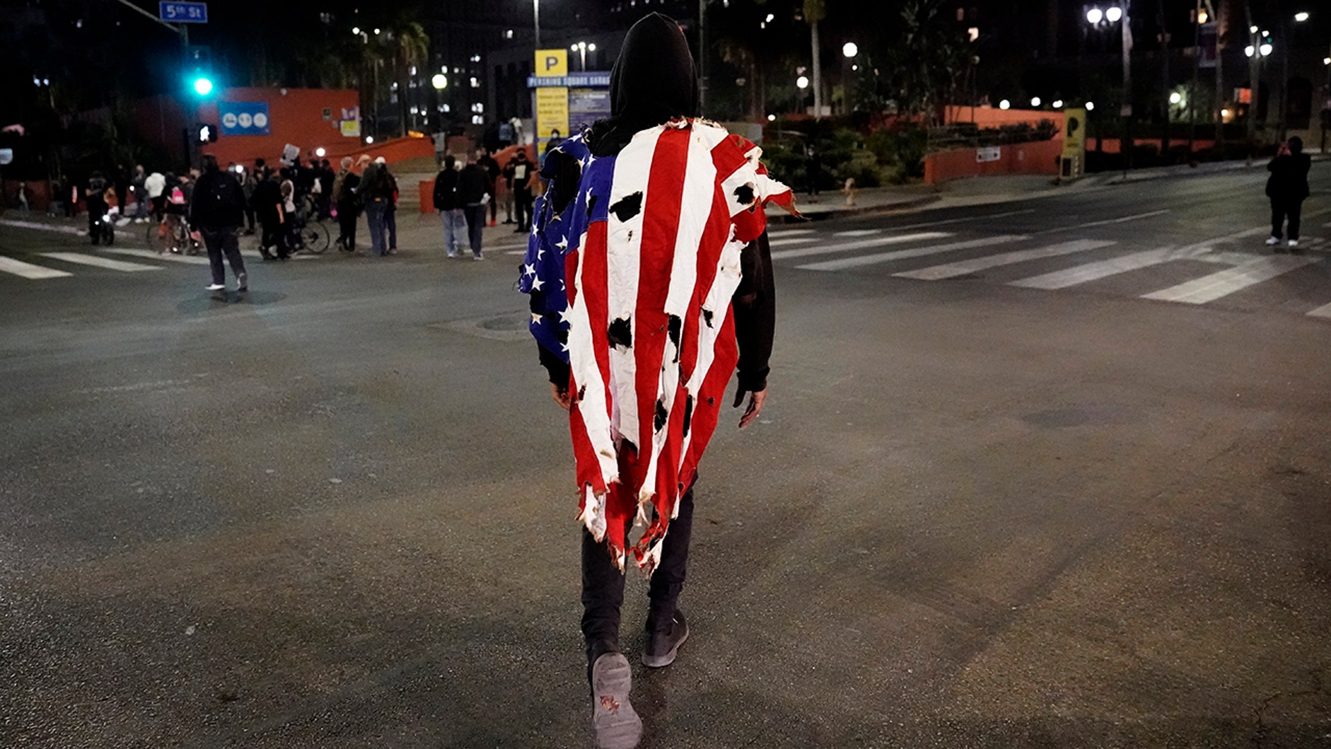 A man wears a partially burned flag during a protest after the Nov. 3 elections, Wednesday, Nov. 4, 2020, in Los Angeles.