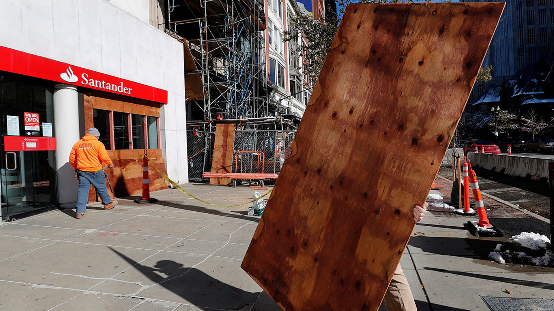 Workers board up the windows of a Santander Bank branch on Boylston Street, Boston, on Saturday, Oct. 31, 2020. (AP Photo/Michael Dwyer)