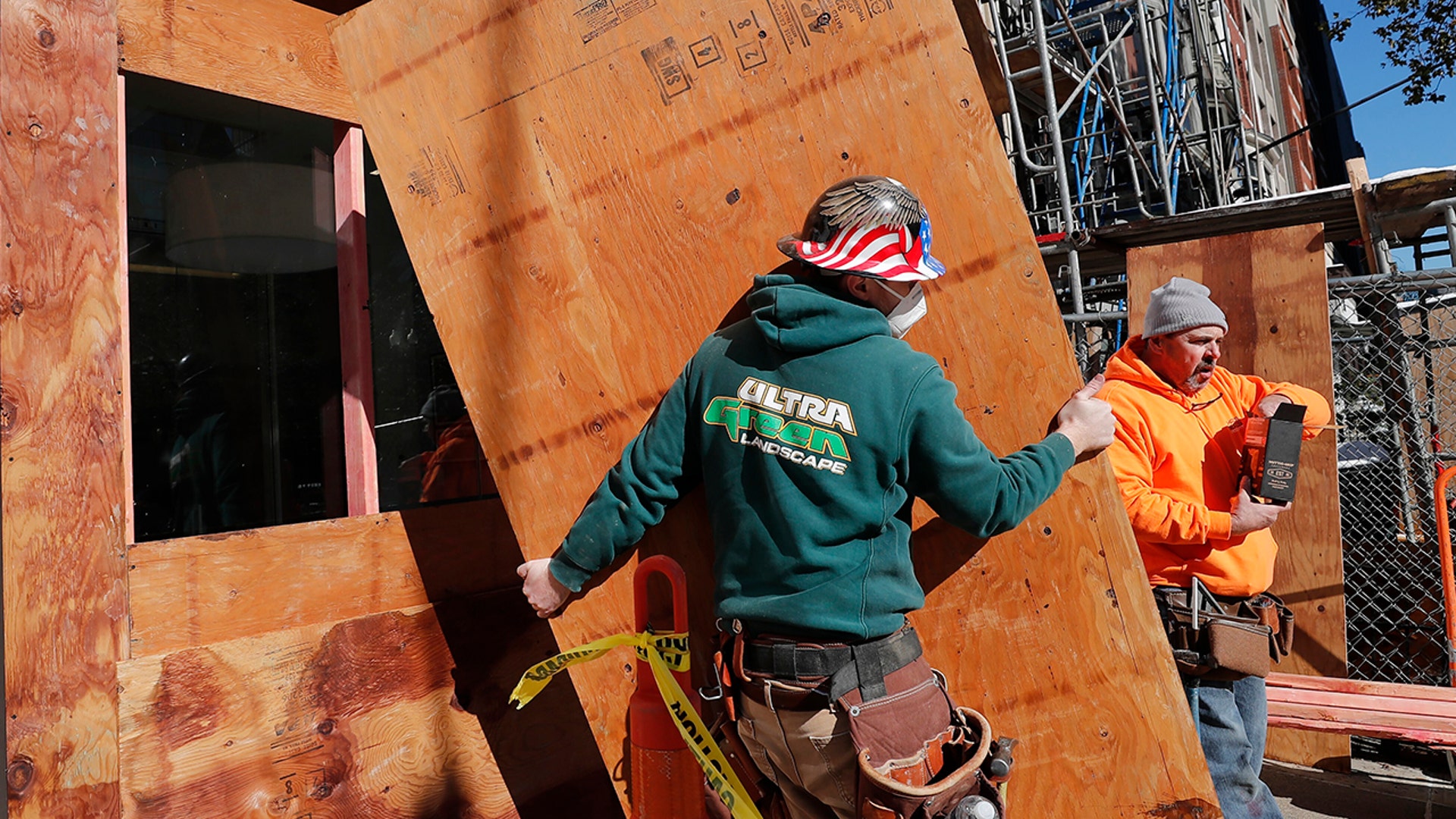 Workers board up the windows of a Santander Bank branch on Boylston Street, Boston, on Saturday, Oct. 31, 2020. Retailers are planning to board up their windows or add extra security personnel in some of their locations ahead of the contentious presidential election on Tuesday. The moves come as retailers are trying to protect themselves against any looting or other civil unrest in a year that has seen widespread protests over social justice that sometimes became violent. (AP Photo/Michael Dwyer)