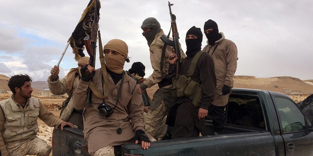 Al Qaeda-linked Nusra Front fighters carry their weapons on the back of a pick-up truck.