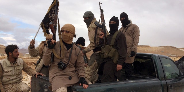 Al Qaeda-linked Nusra Front fighters carry their weapons on the back of a pick-up truck.