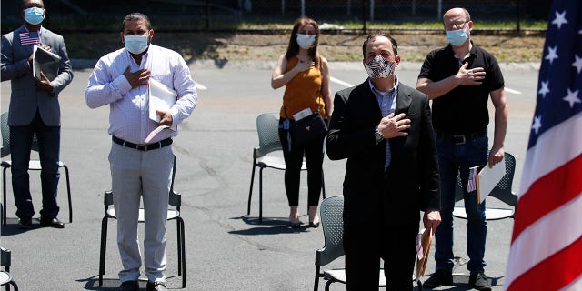 <br>
New U.S. citizens, socially distanced, recite the Pledge of Allegiance outside the U.S. Citizenship and Immigration Services building in Lawrence, Mass., June 4, 2020. (Associated Press)