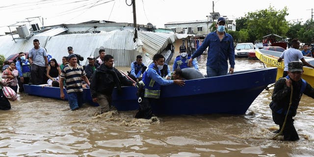 Police help residents move to higher ground after they were rescued from a flooded area, in Planeta, Honduras, Nov. 6. As the remnants of Hurricane Eta moved back over Caribbean waters, governments in Central America worked to tally the displaced and dead, and recover bodies from landslides and flooding that claimed dozens of lives from Guatemala to Panama. (AP Photo/Delmer Martinez)