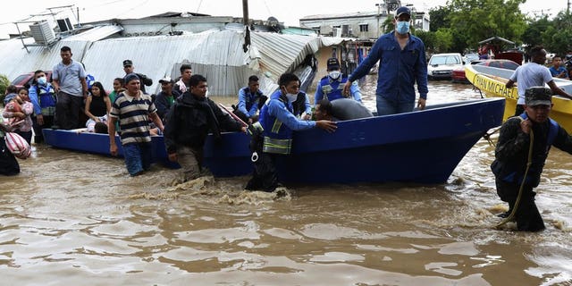 Police help residents move to higher ground after they were rescued from a flooded area, in Planeta, Honduras, Nov. 6. As the remnants of Hurricane Eta moved back over Caribbean waters, governments in Central America worked to tally the displaced and dead, and recover bodies from landslides and flooding that claimed dozens of lives from Guatemala to Panama. (AP Photo/Delmer Martinez)