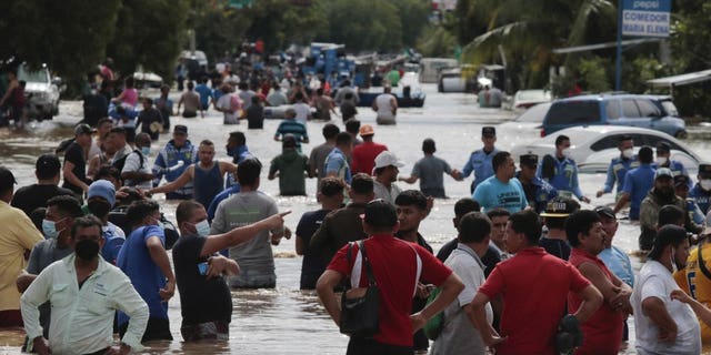 Residents wade through a flooded road in the aftermath of Hurricane Eta in Planeta, Honduras, Nov. 5. The storm that hit Nicaragua as a Category 4 hurricane on Tuesday had become more of a vast tropical rainstorm, but it was advancing so slowly and dumping so much rain that much of Central America remained on high alert. (AP Photo/Delmer Martinez)