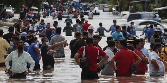 Residents wade through a flooded road in the aftermath of Hurricane Eta in Planeta, Honduras, Nov. 5. The storm that hit Nicaragua as a Category 4 hurricane on Tuesday had become more of a vast tropical rainstorm, but it was advancing so slowly and dumping so much rain that much of Central America remained on high alert. (AP Photo/Delmer Martinez)