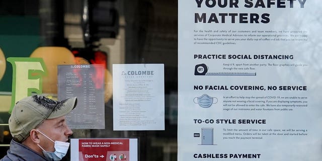 <br>In this Nov. 12, file photo, a man walks past a coffee shop as the store displays information signs in Chicago. With the coronavirus coming back with a vengeance across the country and the U.S. facing a long, dark winter, governors and other elected officials are showing little appetite for reimposing the kind of lockdowns and large-scale business closings seen last spring. (AP Photo/Nam Y. Huh, File)