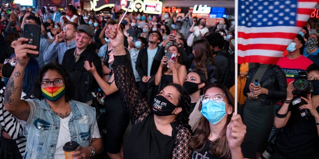 People in New York's Times Square look up at a monitor as President-elect Joe Biden addresses the nation, Saturday, Nov. 7, 2020. (AP Photo/Craig Ruttle)