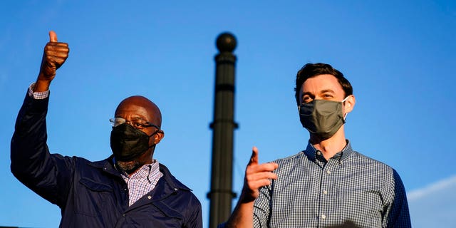 Georgia Democratic candidates for U.S. Senate Raphael Warnock, left, and Jon Ossoff, right, gesture toward a crowd during a campaign rally on Sunday, Nov. 15, 2020, in Marietta, Ga.