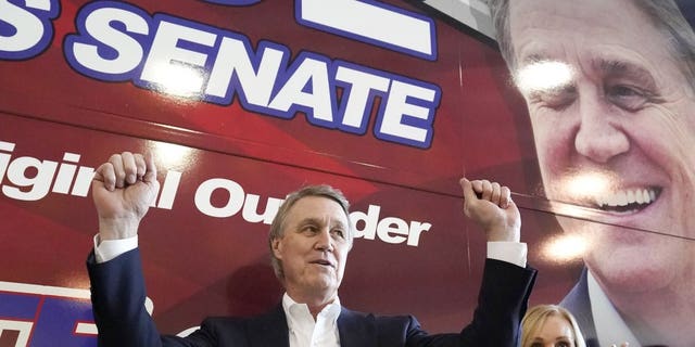 In this Nov. 2, 2020 photo, Sen. David Perdue and his wife Bonnie react during a campaign stop at Peachtree Dekalb Airport in Atlanta. Perdue earlier this year was cleared of wrongdoing by multiple investigations into different stock trades earlier this year. Perdue has stopped trading individudal stocks. (AP Photo/John Bazemore)