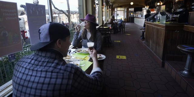 In this Nov. 12 photo, a couple eat inside at the Buena Vista Cafe during the coronavirus outbreak in San Francisco. With the coronavirus coming back with a vengeance across the country and the U.S. facing a long, dark winter, governors and other elected officials are showing little appetite for reimposing the kind of lockdowns and large-scale business closings seen last spring. (AP Photo/Jeff Chiu, File)