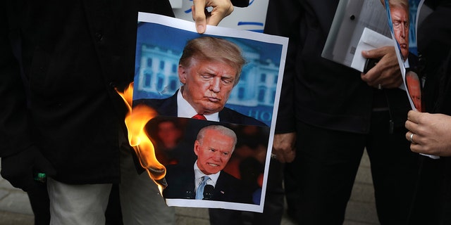 A group of protesters burn photos of US President Donald Trump, above, and President-elect Joe Biden during a rally outside Iran's Foreign Ministry on Saturday, November 28, 2020, a day after the murder of Mohsen Fakhrizadeh, a Iranian.  scientist linked to the country's nuclear program by unknown assailants near Tehran.  (AP Photo / Vahid Salemi)