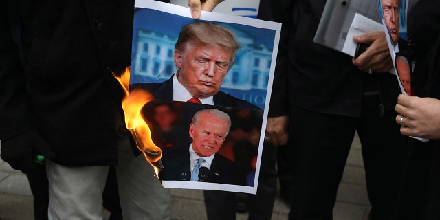 A group of protesters burn pictures of the U.S. President Donald Trump, top, and the President-elect Joe Biden in a gathering in front of Iranian Foreign Ministry on Saturday, Nov. 28, 2020, a day after the killing of Mohsen Fakhrizadeh an Iranian scientist linked to the country's nuclear program by unknown assailants near Tehran. (AP Photo/Vahid Salemi)