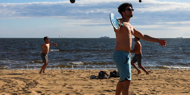 A group of men play sports on the St Kilda beach in Melbourne, Australia, Wednesday, Oct. 28, 2020. Melbourne, Australia's former coronavirus hotspot, emerged from a lockdown at midnight Tuesday, restaurants, cafes and bars were allowed to open and outdoor contact sports can resume. (AP Photo/Asanka Brendon Ratnayake)