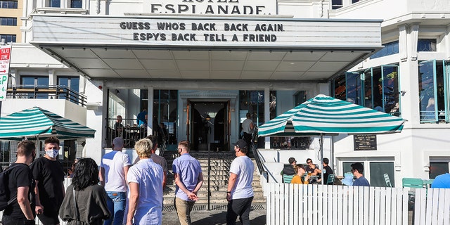 People line up outside a popular pub and restaurant in St Kilda in Melbourne, Australia, Wednesday, Oct. 28, 2020. Melbourne, Australia's former coronavirus hotspot, emerged from a lockdown at midnight Tuesday, restaurants, cafes and bars were allowed to open and outdoor contact sports can resume. (AP Photo/Asanka Brendon Ratnayake)