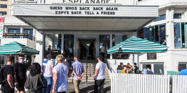 People line up outside a popular pub and restaurant in St Kilda in Melbourne, Australia, Wednesday, Oct. 28, 2020. Melbourne, Australia's former coronavirus hotspot, emerged from a lockdown at midnight Tuesday, restaurants, cafes and bars were allowed to open and outdoor contact sports can resume. (AP Photo/Asanka Brendon Ratnayake)