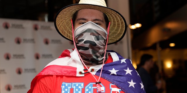 In this Sept. 29, 2020 file photo, Eddie Collantes stands with an American flag draped around his shoulders as he attends a debate watch party hosted by the Miami Young Republicans, Latinos for Trump, and other groups in Miami.
