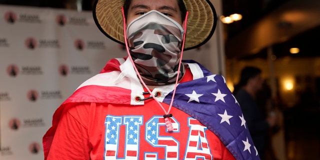 In this Sept. 29, 2020 file photo, Eddie Collantes stands with an American flag draped around his shoulders as he attends a debate watch party hosted by the Miami Young Republicans, Latinos for Trump, and other groups in Miami.