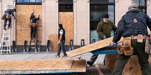 Ahead of the presidential election, workers with Baguer Construction LLC board up a Walgreens on U Street NW, Friday, Oct. 30, 2020, in Washington. The site manager said they had been hired to put protective coverings on several Walgreens throughout the city. (AP Photo/Jacquelyn Martin)