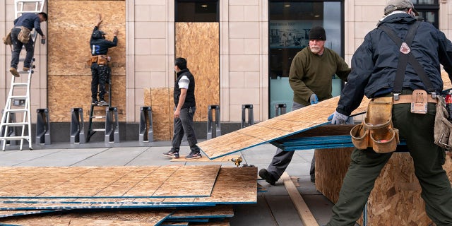 Ahead of the presidential election, workers with Baguer Construction LLC board up a Walgreens on U Street NW, Friday, Oct. 30, 2020, in Washington. The site manager said they had been hired to put protective coverings on several Walgreens throughout the city. (AP Photo/Jacquelyn Martin)