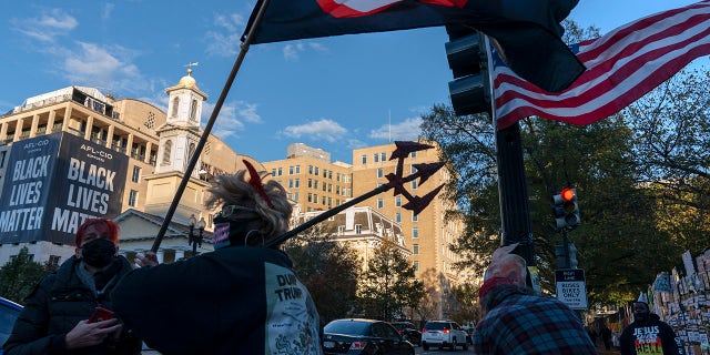 Nadine Seiler, of Waldorf, Md., center, wears a "devil Trump" costume while protesting against President Donald Trump, Friday, Oct. 30, 2020, on the section of 16th Street renamed Black Lives Matter Plaza near the White House in Washington. (AP Photo/Jacquelyn Martin)