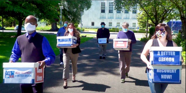 This photo from video provided by the Yes on Measure 110 Campaign shows volunteers delivering boxes containing signed petitions in favor of the measure to the Oregon Secretary of State's office in Salem on June 26, 2020. 