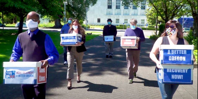 This photo from video provided by the Yes on Measure 110 Campaign shows volunteers delivering boxes containing signed petitions in favor of the measure to the Oregon Secretary of State's office in Salem on June 26, 2020.