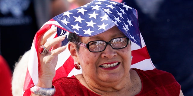A supporter of Vice President Mike Pence smiles as she waits for Pence to speak at a campaign rally at Tucson International Airport Friday, Oct. 30, 2020, in Tucson, Ariz. (AP Photo/Ross D. Franklin)