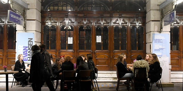 People take a drink outside a theatre on Saint Martin's Lane in central London, Saturday, Oct. 31, 2020. Earlier Saturday British Prime Minister Boris Johnson announced England will start a month long lockdown next week. Johnson says the new measures will begin Thursday and last until Dec. 2. (AP Photo/Alberto Pezzali, Pool)