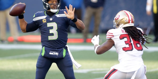 Seattle Seahawks quarterback Russell Wilson (3) makes a touchdown pass to wide receiver DK Metcalf (not shown) as San Francisco 49ers safety Marcell Harris, right, pressures during the first half of an NFL football game, Sunday, Nov. 1, 2020, in Seattle. (AP Photo/Scott Eklund)