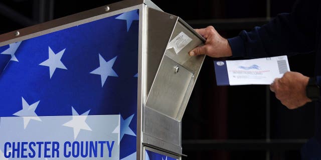 In this Oct. 23, 2020, file photo, a man drops off his ballot for the 2020 General Election in the United States outside the Chester County Government Services Center in West Chester, Penn. (AP Photo/Matt Slocum, File)