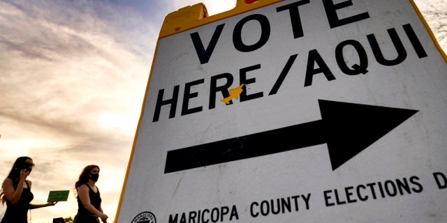 Voters deliver their ballot to a polling station, Tuesday, Nov. 3, 2020, in Tempe, Arizona.