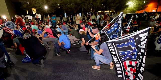 Trump supporters kneel as they rally Wednesday night outside the Maricopa County Recorders Office in Phoenix. (Associated Press)