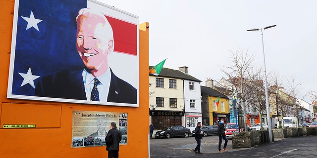A man stops to read a plaque below a mural of US presidential candidate Joe Biden in his ancestral home of Ballina, Ireland, Thursday, Nov. 5, 2020. (Brian Lawless/PAvia AP)