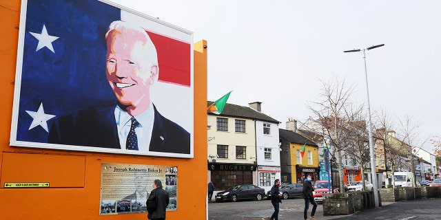 A man stops to read a plaque below a mural of US presidential candidate Joe Biden in his ancestral home of Ballina, Ireland, Thursday, Nov. 5, 2020. (Brian Lawless/PAvia AP)