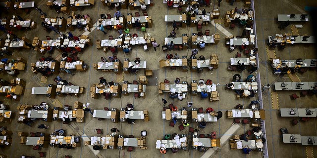 Officials count early votes at the Roberto Clemente Coliseum where social distancing is possible amid the COVID-19 pandemic, during general elections in San Juan, Puerto Rico, Tuesday, Nov. 3, 2020. In addition to electing a governor, Puerto Ricans are voting in a non-binding referendum on statehood. (AP Photo/Carlos Giusti)