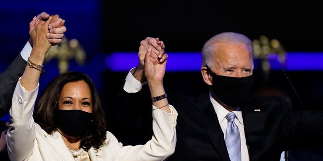 Vice President-elect Kamala Harris holds hands with President-elect Joe Biden and her husband Doug Emhoff as they celebrate Saturday, Nov. 7, 2020, in Wilmington, Del.