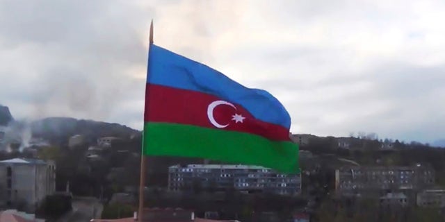 This photo taken from a video released by Azerbaijan's Defense Ministry on Monday, Nov. 9, 2020, shows Azerbaijan's national flag with the city of Shushi in the background, in the separatist region of Nagorno-Karabakh. President Ilham Aliyev said Sunday that Azerbaijani forces had taken control of the strategically important city in Nagorno-Karabakh, where fighting with Armenia has raged for over a month. (Azerbaijan's Defense Ministry via AP)