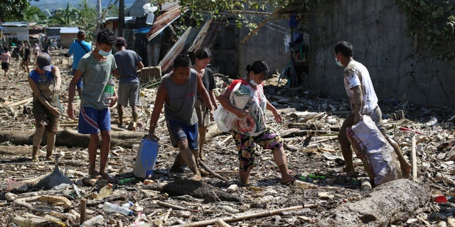 Residents walk through mud and debris at the typhoon-damaged Kasiglahan village in Rodriguez, Rizal province, Philippines on Friday, Nov. 13, 2020. Thick mud and debris coated many villages around the Philippine capital Friday after Typhoon Vamco caused extensive flooding that sent residents fleeing to their roofs and killing dozens of people. (AP Photo/Aaron Favila)