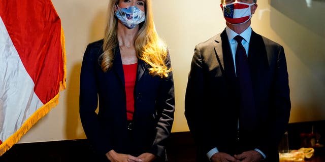 Republican candidates for U.S. Senate Sen. Kelly Loeffler, left, and Sen. David Perdue wait to speak at a campaign rally on Friday, Nov. 13, 2020, in Cumming, Ga. (AP Photo/Brynn Anderson)