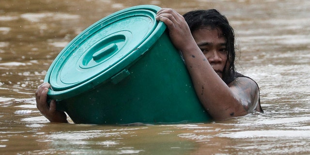 A man uses a plastic canister to float while negotiating rising floodwaters from Typhoon Vamco in Marikina, Philippines, on Thursday, Nov. 12, 2020. Vamco swelled rivers and flooded low-lying areas as it passed over the storm-battered northeastern part of the country. (AP Photo/Aaron Favila)
