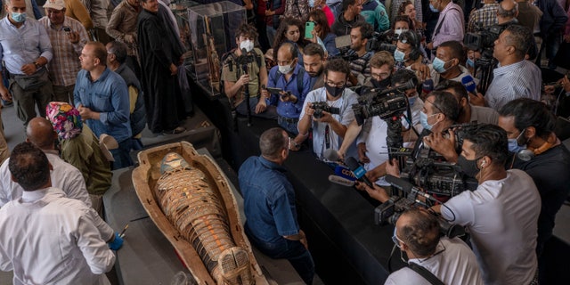 Journalists gather around an ancient sarcophagus more than 2500 years old, discovered in a vast necropolis and Mostafa Waziri, the secretary-general of the Supreme Council of Antiquities, center, in Saqqara, Giza, Egypt, Saturday, Nov. 14, 2020. Egyptian antiquities officials on Saturday announced the discovery of at least 100 ancient coffins, some with mummies inside, and around 40 gilded statues south of Cairo. (AP Photo/Nariman El-Mofty)