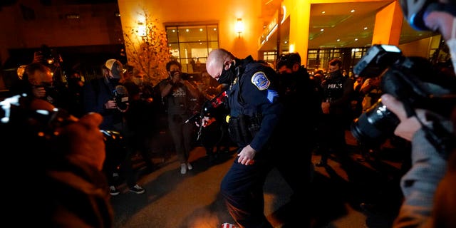 An officer puts up a sign indicating that counter-protesters lit the fire after supporters of President Donald Trump staged pro-Trump marches on November 14 in Washington.  (AP Photo / Julio Cortez)