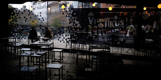 People sit in an empty cafe in downtown Belgrade, Serbia, Monday, Nov. 16, 2020.
