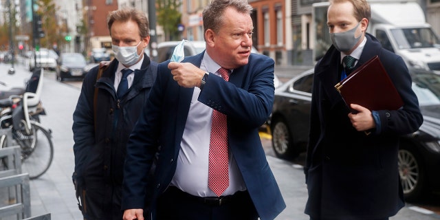 Britain's chief negotiator David Frost, center, removes his face mask to talk to the media as he arrives for Brexit talks with EU chief negotiator Michel Barnier in Brussels, Monday, Nov. 16, 2020. Britain and the EU say any post-Brexit trade deal must be agreed upon by mid-November so it can be ratified by the end of the year, but the negotiations remain stuck on key issues like fishing rights and competition rules. (AP Photo/Francisco Seco)